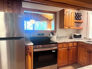 A kitchen with wooden cabinets, a stainless steel refrigerator, a built-in oven, and a microwave. - NEW: Lakefront Cottage on Kennebunk Pond, sleeps 6 (Lyman)