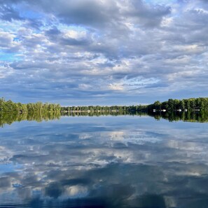 A calm lake with a clear reflection of the sky and trees.