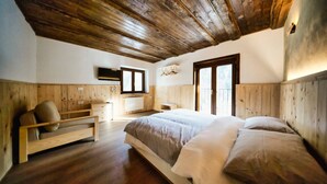 Ein Schlafzimmer mit Holzbalkendecke, einem Bett mit weißer Bettwäsche, einer Holzbank und einem Fenster mit Aussicht.