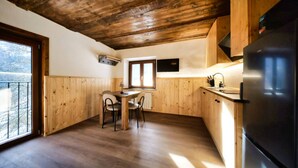 Eine Küche mit Holzausstattung, einem Esstisch mit Stühlen, einem Fenster und einem Kühlschrank.