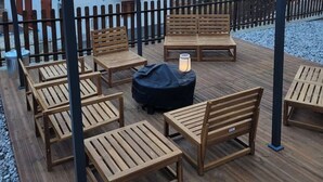 Eine Holzterrasse mit Sitzgelegenheiten im Freien und einem Blick auf die Berge.