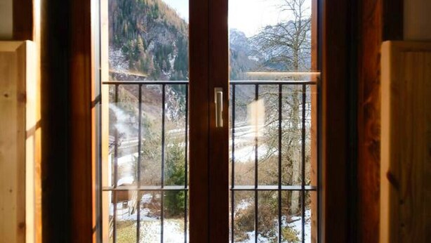Eine Holztür mit Blick auf eine verschneite Landschaft und Berge.