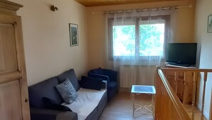 Een houten plafond, een bank, een televisie en een raam met gordijnen.