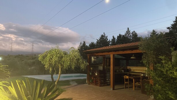 Een terras met een zwembad, een houten pergola en een pad van bakstenen.