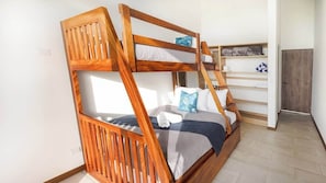 A bunk bed with wooden railings, a white wall, and a small shelf with towels. - Colibri Villas del Bosque at La Fortuna (La Fortuna)