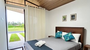 Een slaapkamer met een bed, nachtkastje, plafondlamp en uitzicht op de omgeving.