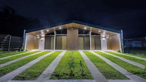 Un bâtiment moderne doté d’un toit en pente, de grandes fenêtres et d’une entrée bien éclairée.