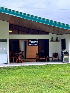 A covered outdoor area with a TV screen, wooden furniture, and a grill. - Colibri Villas del Bosque at La Fortuna (La Fortuna)