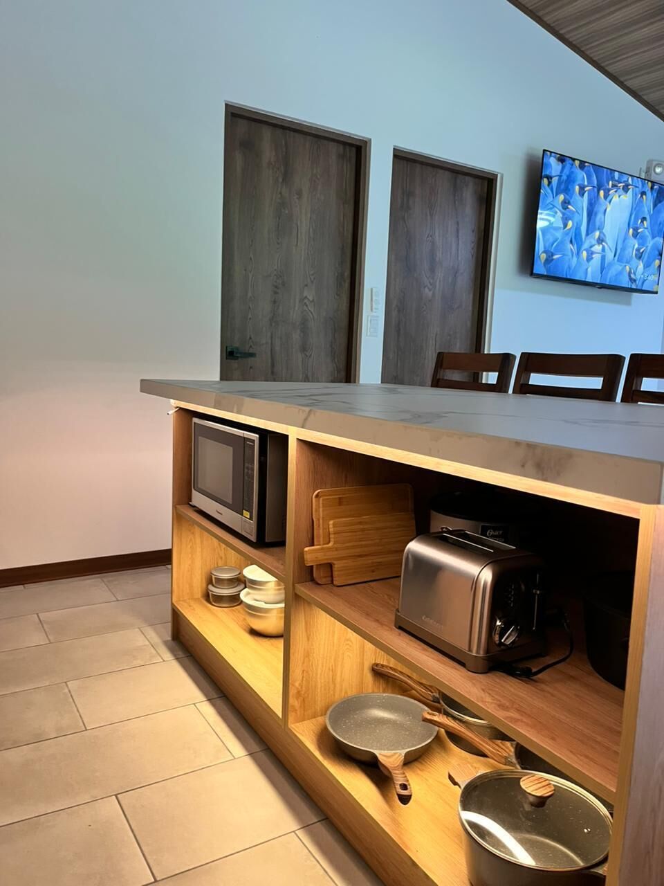 Una cocina compacta con microondas, tostadora y sartén sobre una estante de madera.