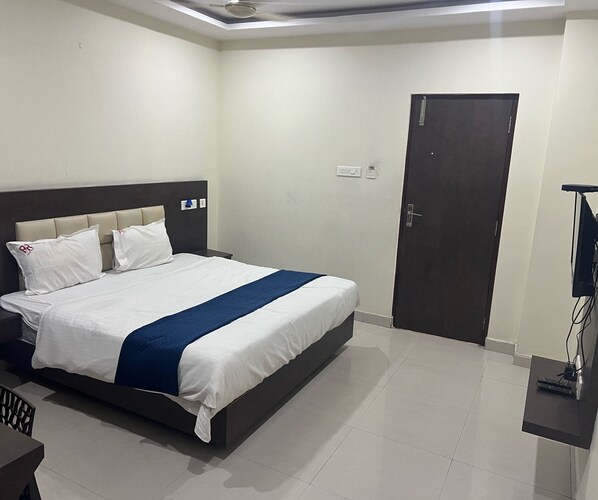 A hotel room with a bed, a desk, and a door. - Townhouse Kanithi Road (Visakhapatnam)
