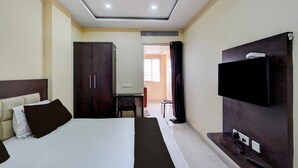 Een hotelkamer met een bed, een kledingkast, een bureau met stoel, een televisie en een zichtbare badkamer door een open deur.