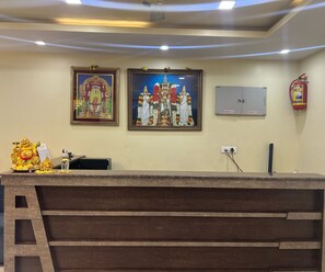 A reception desk with framed religious paintings, a fire extinguisher, and a power outlet. - Townhouse Kanithi Road (Visakhapatnam)