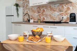 Una mesa de desayuno con un bol de fruta, muffins y tazas de café en una cocina moderna.