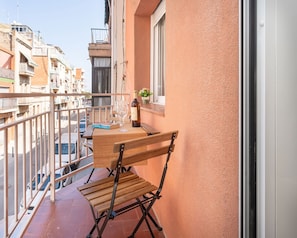 Een balkon met een houten stoel, een wijnfles en een glas op een tafel.
