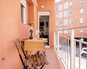 Un balcon avec une table, une chaise, une bouteille de vin et un verre.