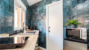Uma cozinha compacta com máquina de lavar louça, micro-ondas e um vaso de planta.