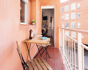 Ein Balkon mit Tisch, Stühlen, einer Flasche und Gläsern.
