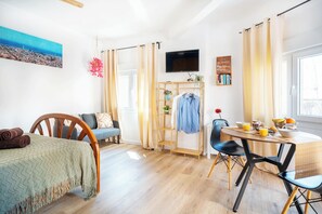 Ein Zimmer mit einem Bett, einem Schreibtisch mit Stuhl, einem Fernseher, einem Bücherregal und einem Fenster mit Vorhängen.