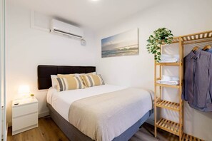 A neatly arranged bedroom with a bed, bedside table, and a wooden wardrobe with folded clothes. - Apart. 3 bedr. 8'. Fira Barcelona and 20' Bcn center (L'Hospitalet de Llobregat)