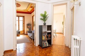 A hallway with a wooden floor, a bookshelf, and a radiator. - Apartment Gran Via 7 Bedrooms/14px-8 min Paseo Gracia (Barcelona)
