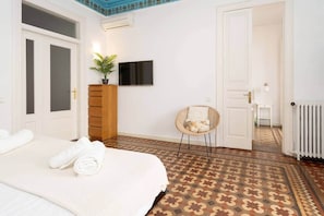 A bedroom with a bed, a dresser, a chair, a TV, and a radiator. - Apartment Gran Via 7 Bedrooms/14px-8 min Paseo Gracia (Barcelona)