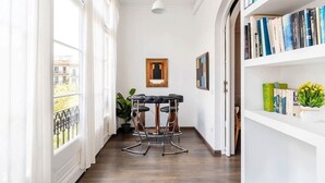 A narrow hallway with a bar stool, a bookshelf, and a framed picture on the wall. - Apartment Luxe Gran Via 5 Bedrooms - 8 min Paseo Gracia (Barcelona)