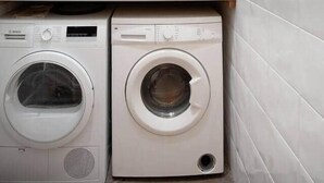 A laundry room with two front-loading washing machines, a small sink, and a window above the machines. - Apartment Luxe Gran Via 5 Bedrooms - 8 min Paseo Gracia (Barcelona)
