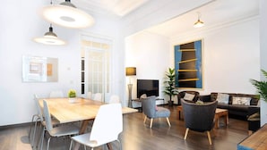 A modern living room with a dining area, a sofa set, and a TV. - Apartment Luxe Gran Via 5 Bedrooms - 8 min Paseo Gracia (Barcelona)