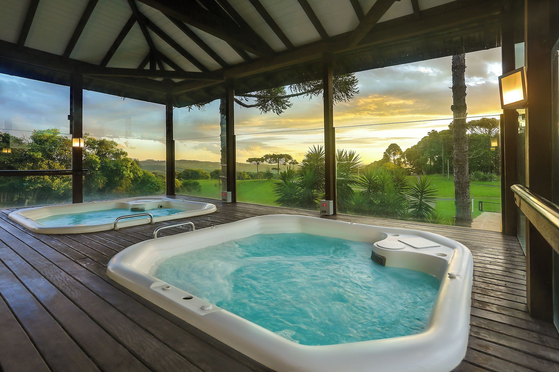 A hot tub area with a wooden deck and a view of a green landscape.