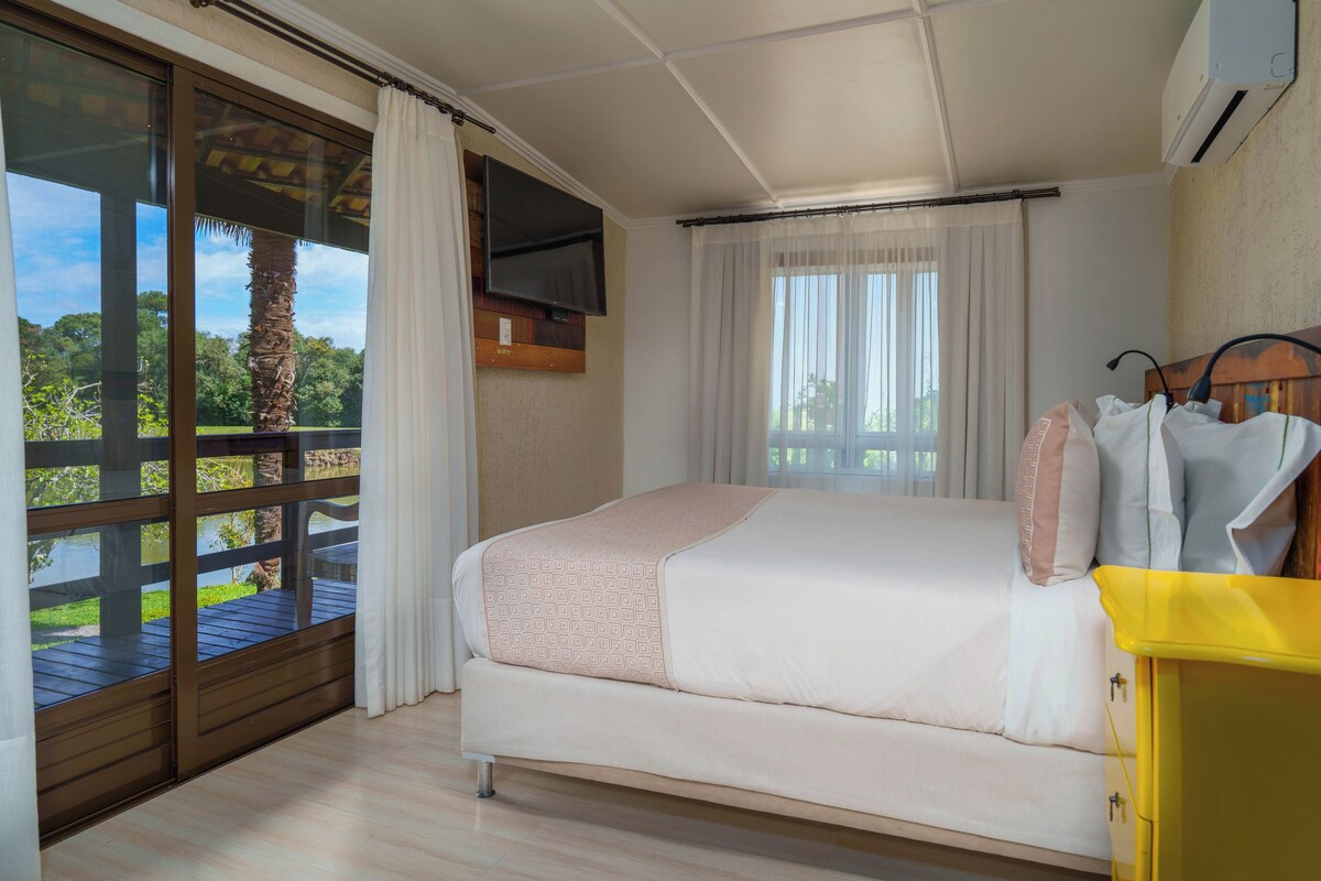Un dormitorio con cama, ventana con cortinas, vista a un balcón y aire acondicionado de pared.
