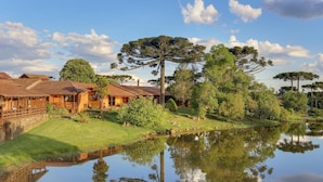 Propiedad junto al lago con cabañas de madera, un estanque y árboles circundantes.