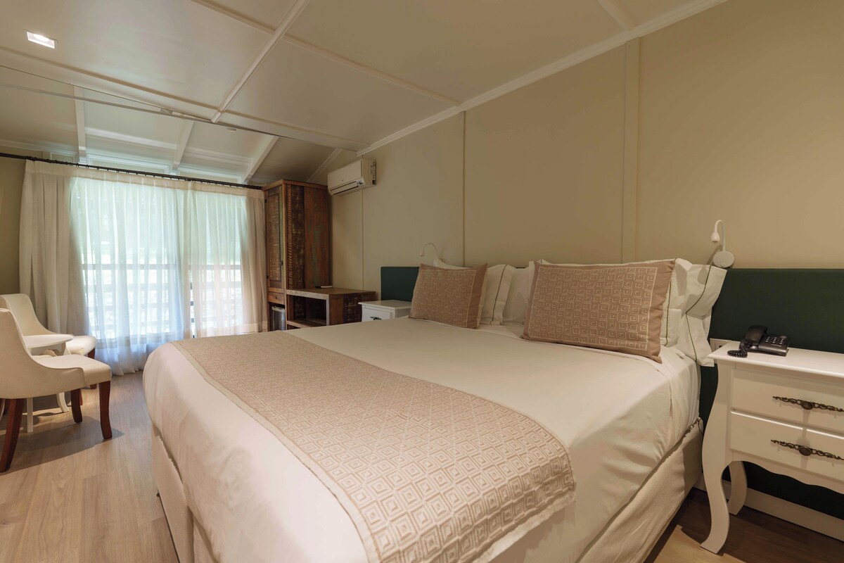 Una habitación de hotel con una cama grande, un escritorio, una silla y un equipo de aire acondicionado.