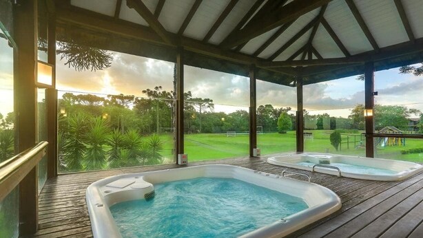 Terraza de madera con dos jacuzzis y vista a un campo de golf.