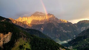 Un paysage de montagne avec un arc-en-ciel, une forêt dense et une vallée.