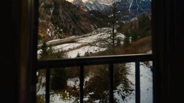 Un paysage de montagne vu à travers une fenêtre à cadre en bois.