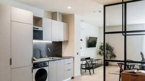 A modern kitchen with built-in appliances, a dining area with a table and chairs, and a sliding glass door leading to a balcony.