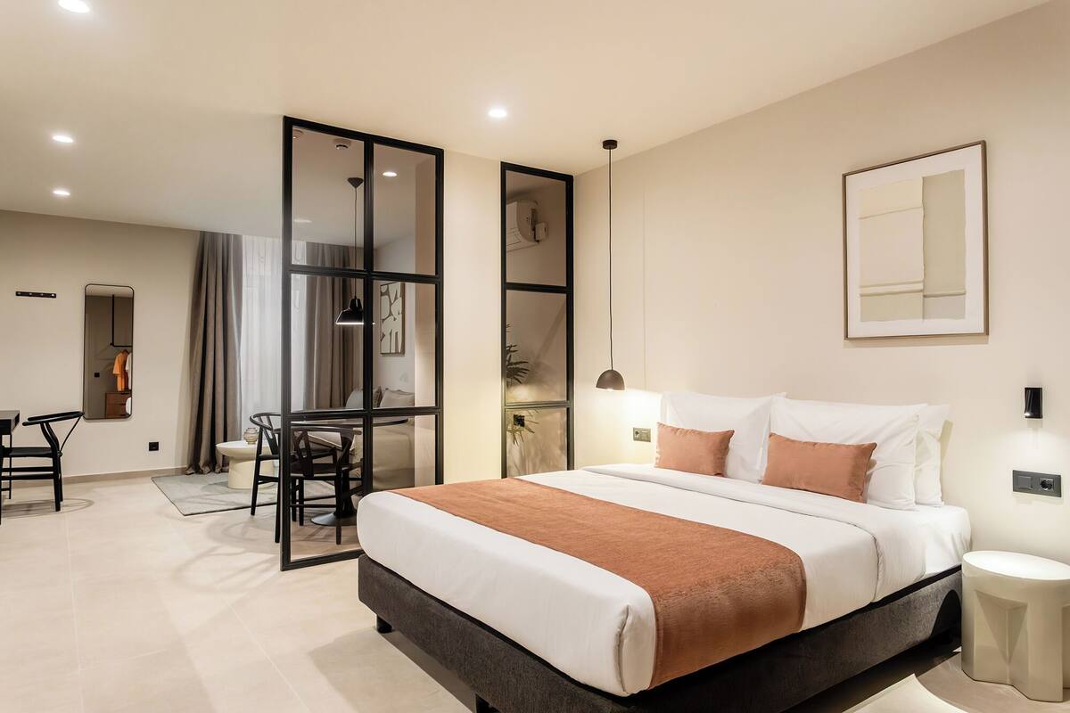 A modern hotel room with a large bed, a desk, and a chair.