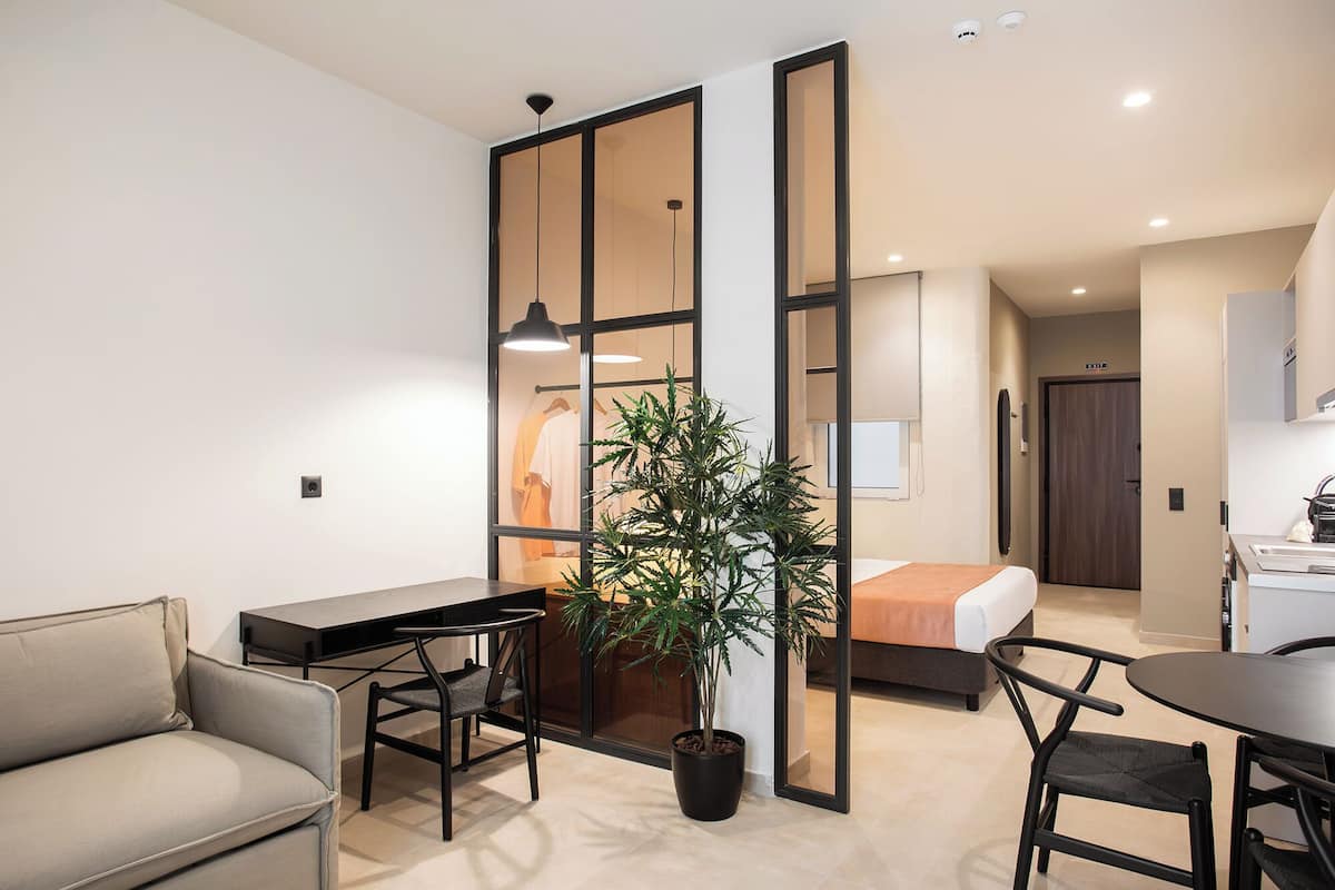 A modern apartment with a dining area, a living room, a kitchen, and a sliding door leading to a bedroom.