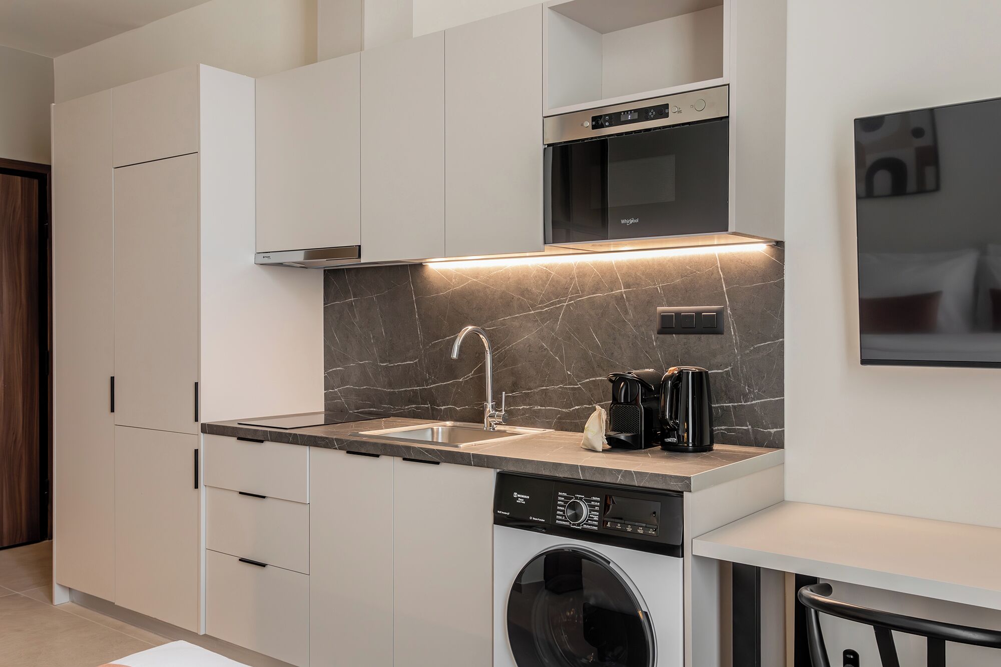 A modern kitchen with a built-in dishwasher, a washing machine, and a microwave.