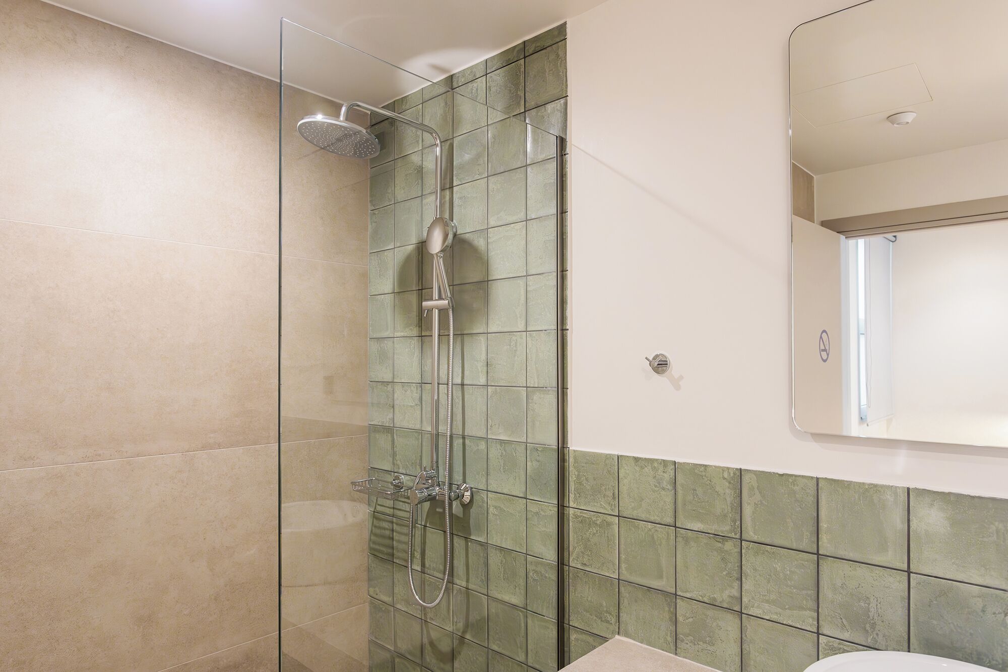 Un baño con ducha de vidrio, inodoro y espejo.