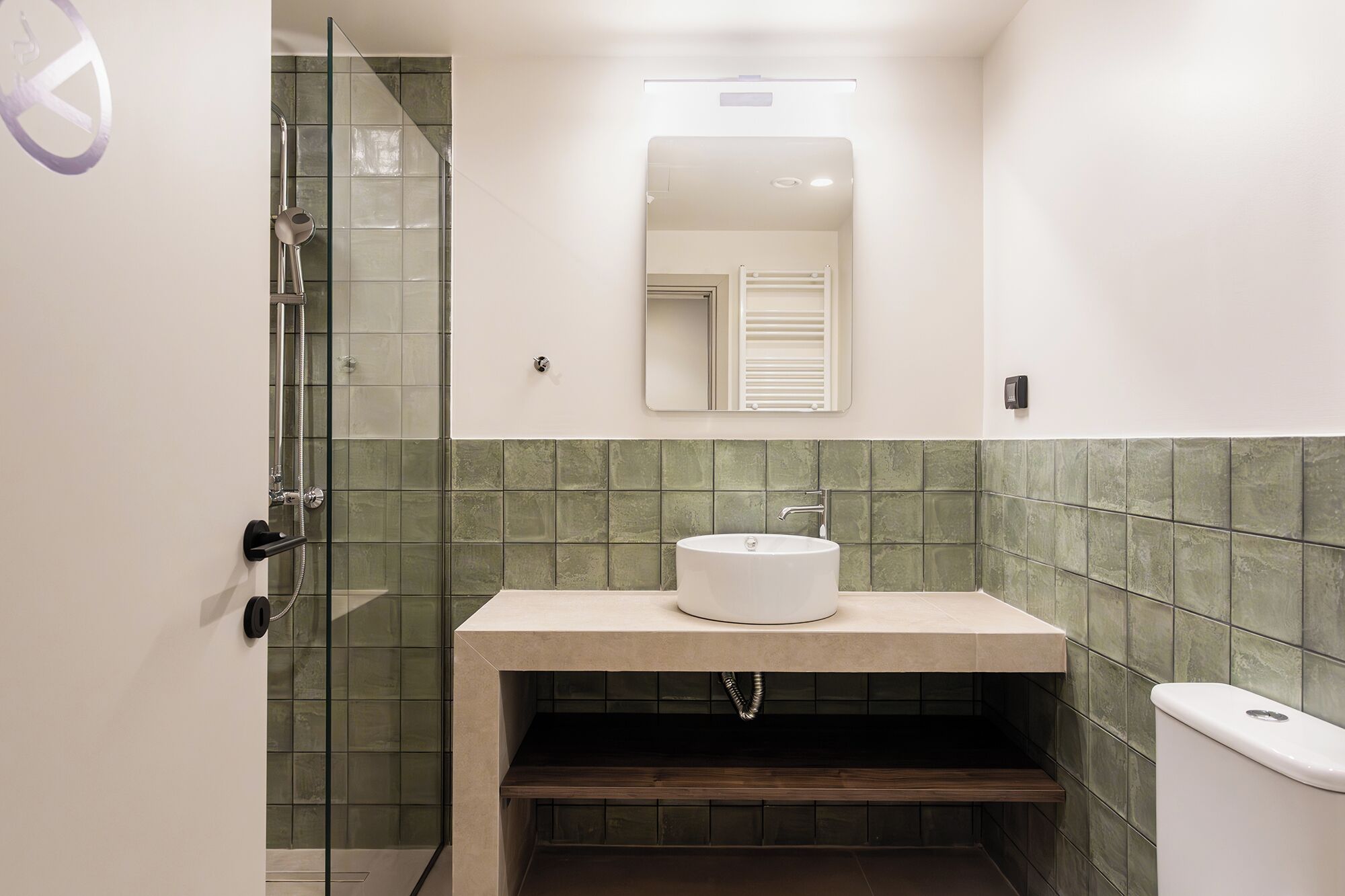 A bathroom with a glass shower enclosure, a sink with a mirror above it, and a toilet.
