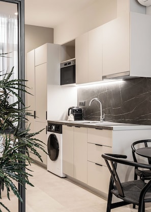 Une cuisine moderne dotée d’appareils électroménagers intégrés, d’un évier et d’un coin repas avec des chaises.