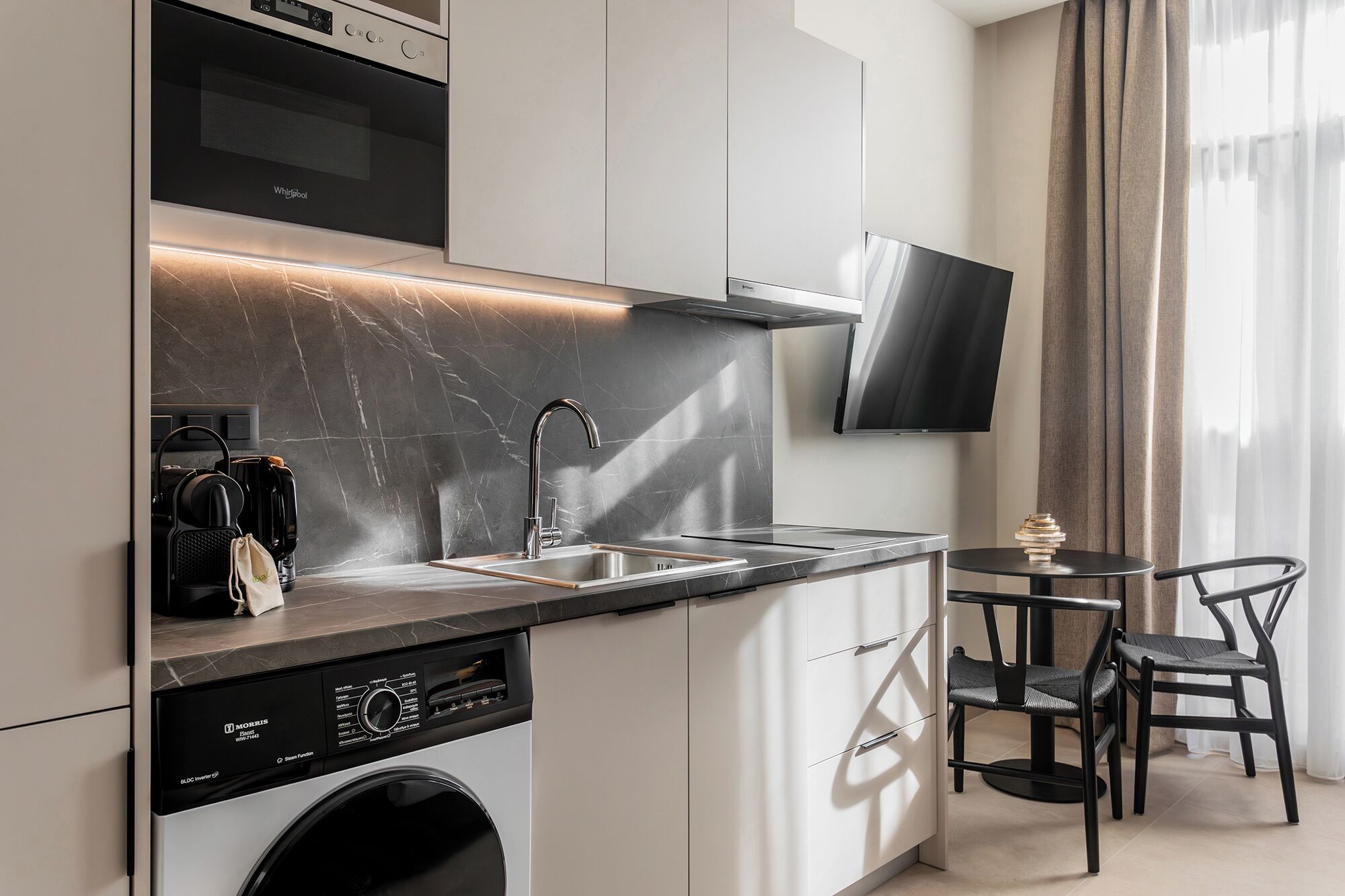 Une cuisine moderne équipée d’un lave-linge intégré, d’un four à micro-ondes et d’un téléviseur à écran plat.