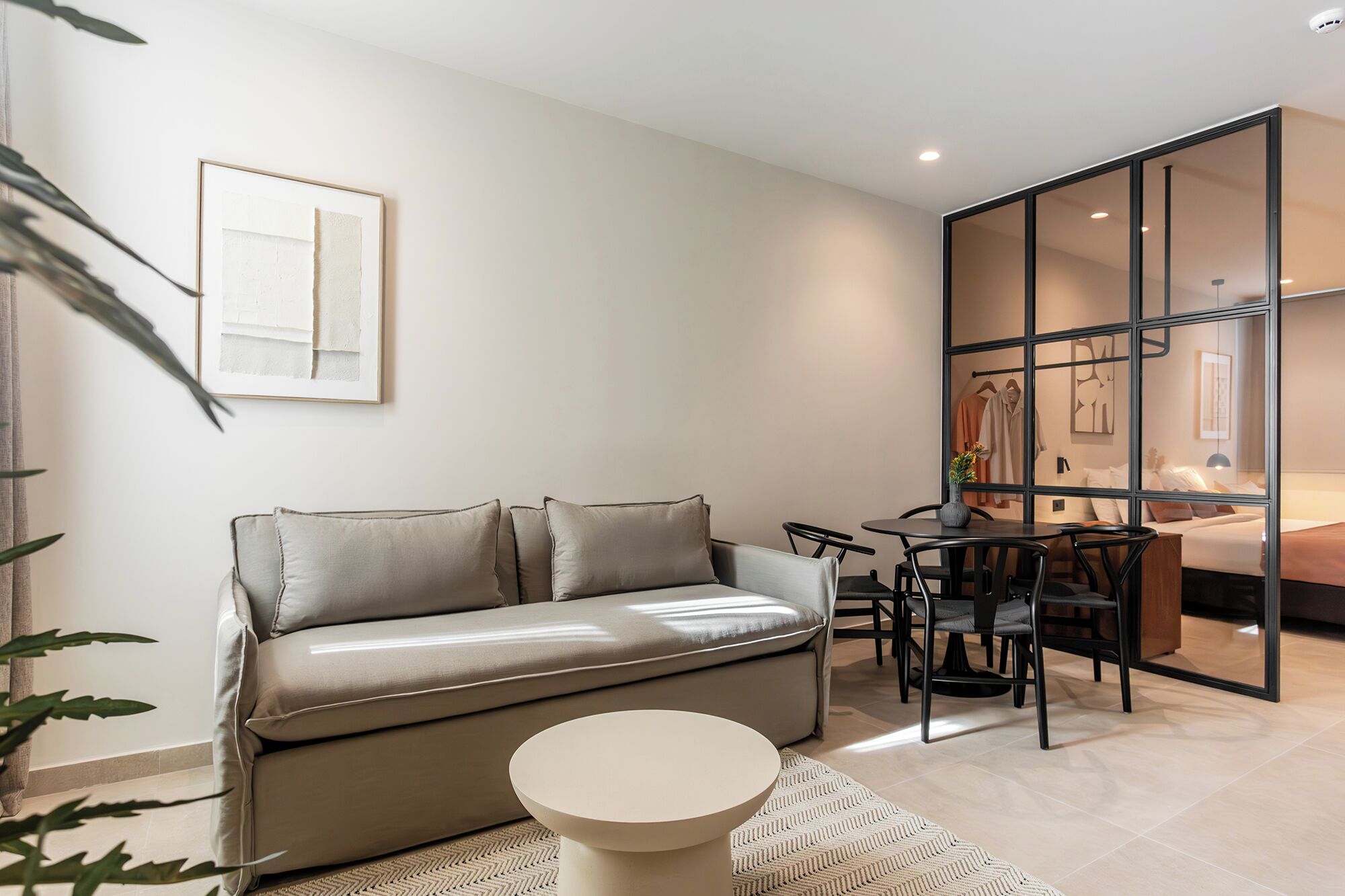 A modern living room with a sofa, a round coffee table, and a dining area with chairs.