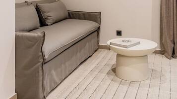 A minimalist room with a sofa, a round table, and a framed artwork on the wall.