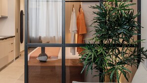 A modern interior with a sliding glass door, a sofa, a potted plant, and a clothing rack.