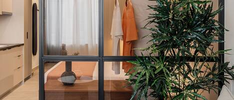 A modern interior with a sliding glass door, a sofa, a potted plant, and a clothing rack.