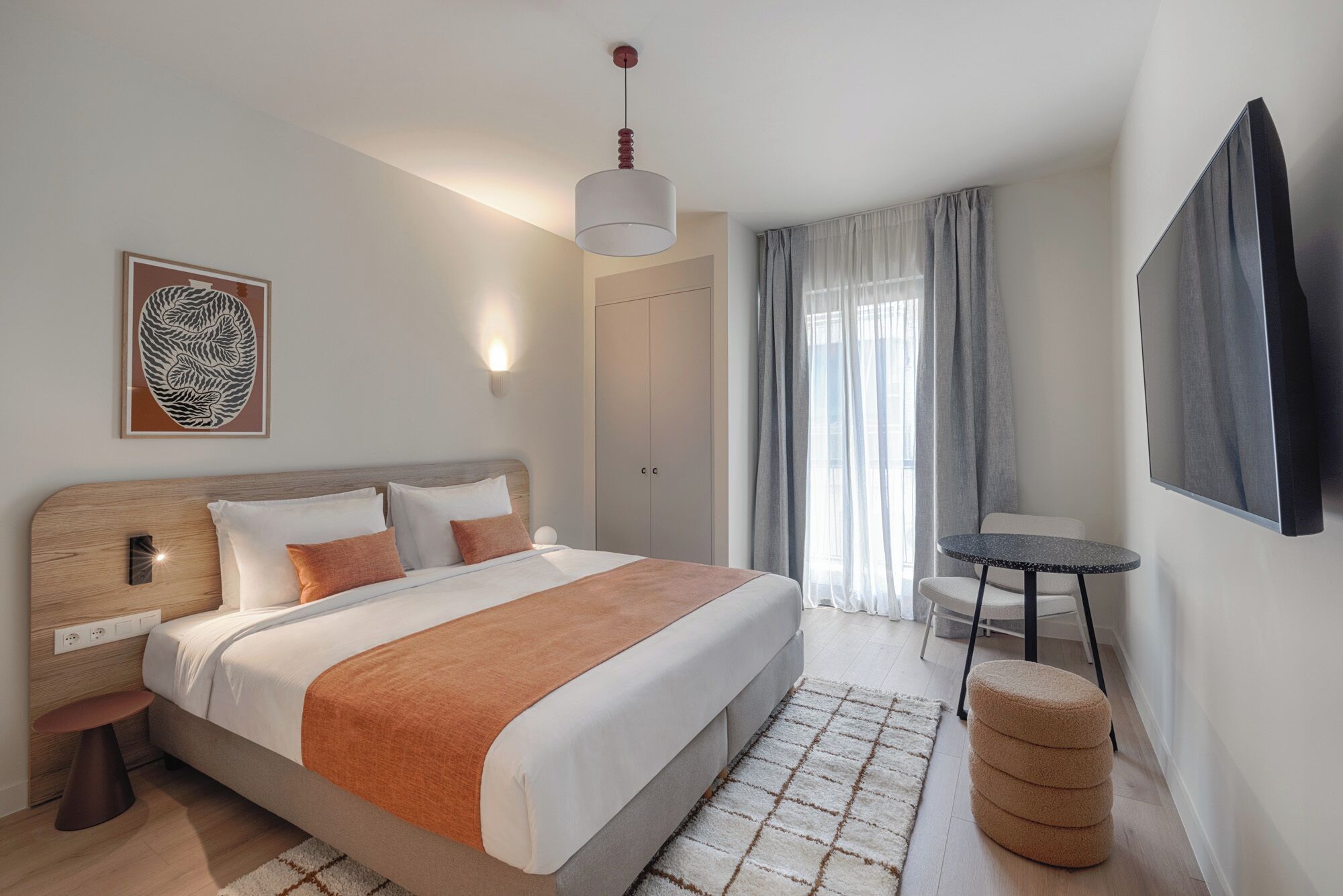 Une chambre d’hôtel moderne avec un grand lit, une table de chevet et une petite table ronde.