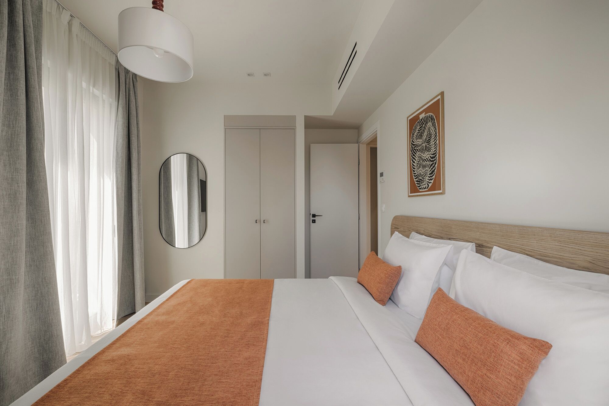 Una camera d'albergo con un letto, uno specchio, una porta e una parete con un'opera d'arte incorniciata.