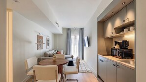 Eine kompakte Wohnung mit Essbereich, Küchenzeile und Wohnbereich inklusive Sofa und Vorhängen.
